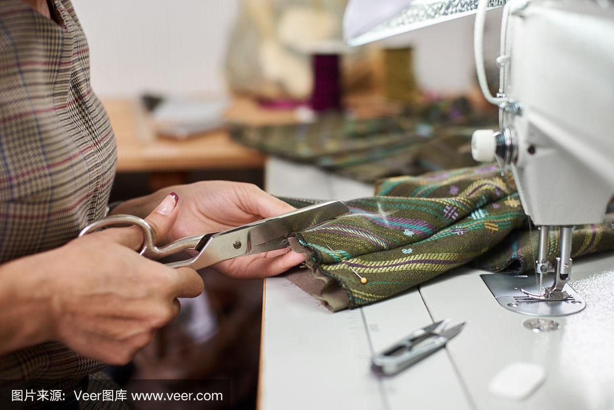 女裁缝在时尚工作室使用现代电动缝纫机制作独家服装.